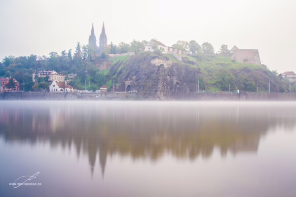 Mlžný pohled na historickou pevnost Vyšehrad s dvojvěžím baziliky sv. Petra a Pavla, odraz ve Vltavě, autor Martin Lukač