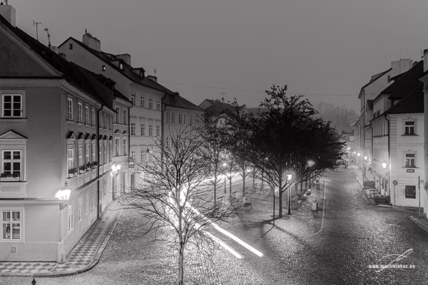 Pohled na ranní Kampu v Praze s oranžovým osvětlením a stopou projíždějícího auta, autor Martin Lukač, černobílá
