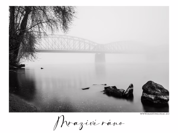 Černobílá fotografie železničního mostu přes Vltavu v ranní mlze, chladná atmosféra a klidná voda, autor Martin Lukač