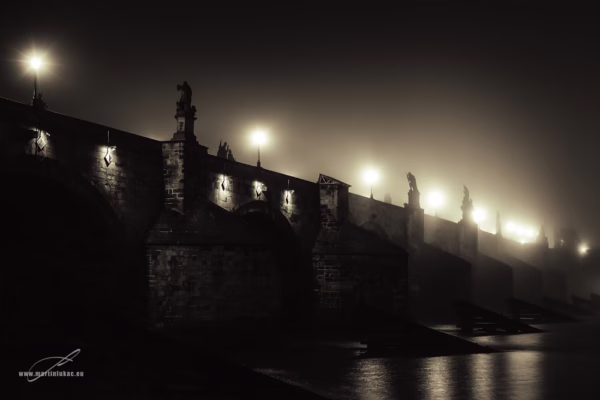 Karlův most v noci zahalený mlhou a osvětlený lucernami, poetická noční fotografie, autor Martin Lukač