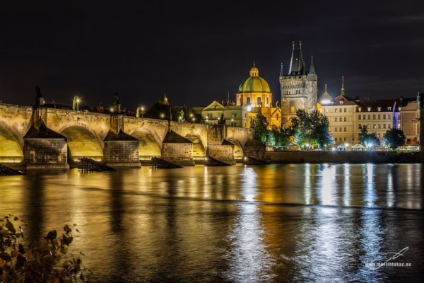 Karlův most nasvícený v noci s odlesky ve Vltavě, autor Martin Lukač