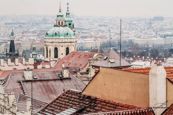 Zimní pohled na zasněžené střechy Malé Strany s dominantou kostela sv. Mikuláše, autor Martin Lukač