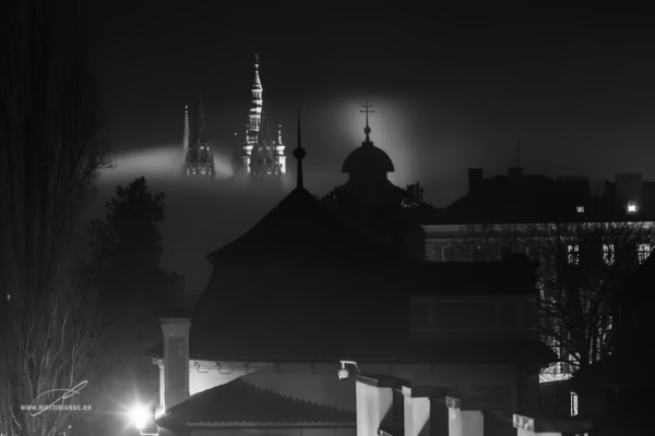 Noční pohled na Pražský hrad s osvícenou katedrálou sv. Víta vystupující z mlhy, autor Martin Lukač, černobílý
