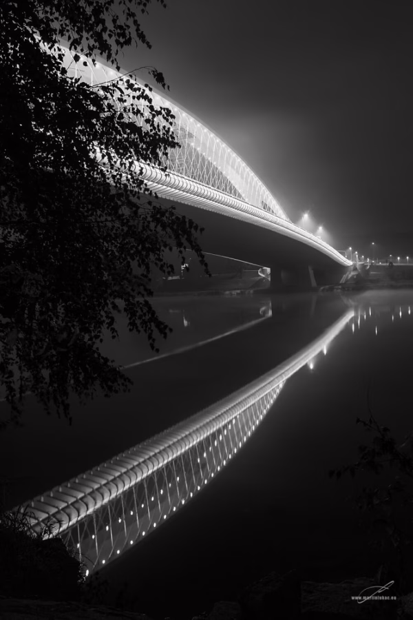Černobílá verze fotografie Trojského mostu v Praze v mlze s odrazem, autor Martin Lukač