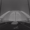 Černobílá fotografie Trojského mostu v mlze s tramvajovými kolejemi a osvětlenou konstrukcí, autor Martin Lukač, černobílý