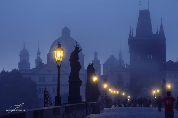 Karlův most za večerní modré hodiny s pouličními lampami a postavami, autor Martin Lukač
