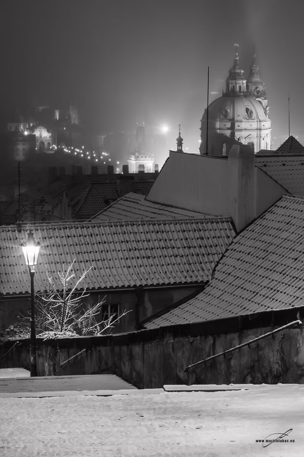 Zimní nálada v Praze s nasvícenými střechami a mlhou v černobílé verzi, autor Martin Lukač, pražský fotograf, www.martinlukac.eu