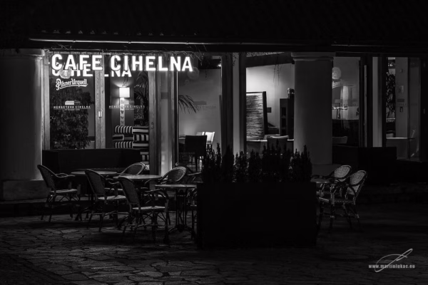 Černobílá fotografie kavárny Cafe Cihelna v Praze, osvětlený interiér a prázdné venkovní posezení v nočním prostředí, autor Martin Lukač, pražský fotograf, www.martinlukac.eu