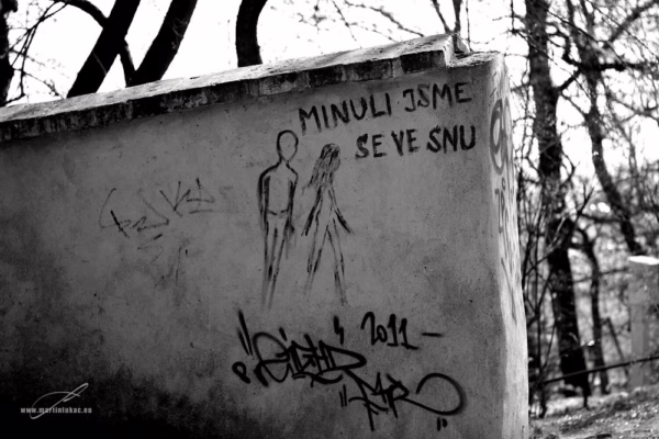 Černobílá fotografie street artu na zdi s nápisem "Minuli jsme se ve snu" a kresbou dvou postav, autor Martin Lukač, pražský fotograf, www.martinlukac.eu