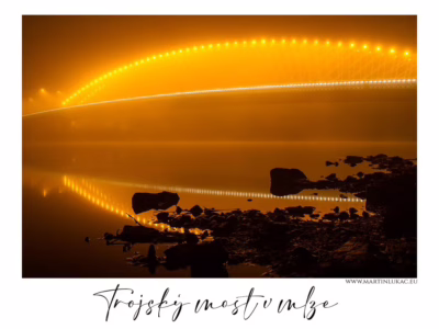 Trojský most v mlze – zlatý oblouk ticha nad řekou Trojský most v Praze nasvícený zlatým světlem, odrážející se v klidné hladině Vltavy, autor Martin Lukač