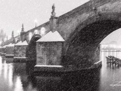 Zimní ticho ukryté pod mostními oblouky... Mostní oblouk a sníh padající na Vltavu v poetické černobílé, autor Martin Lukač, pražský fotograf, www.martinlukac.eu